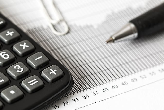 Close-up of a calculator and pen on a bar graph, representing finance and accounting.